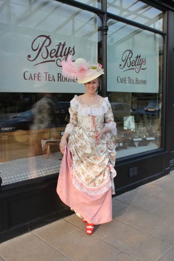 A women dressed like the Victorian times. A voluminous skirt with blouse and headgear.